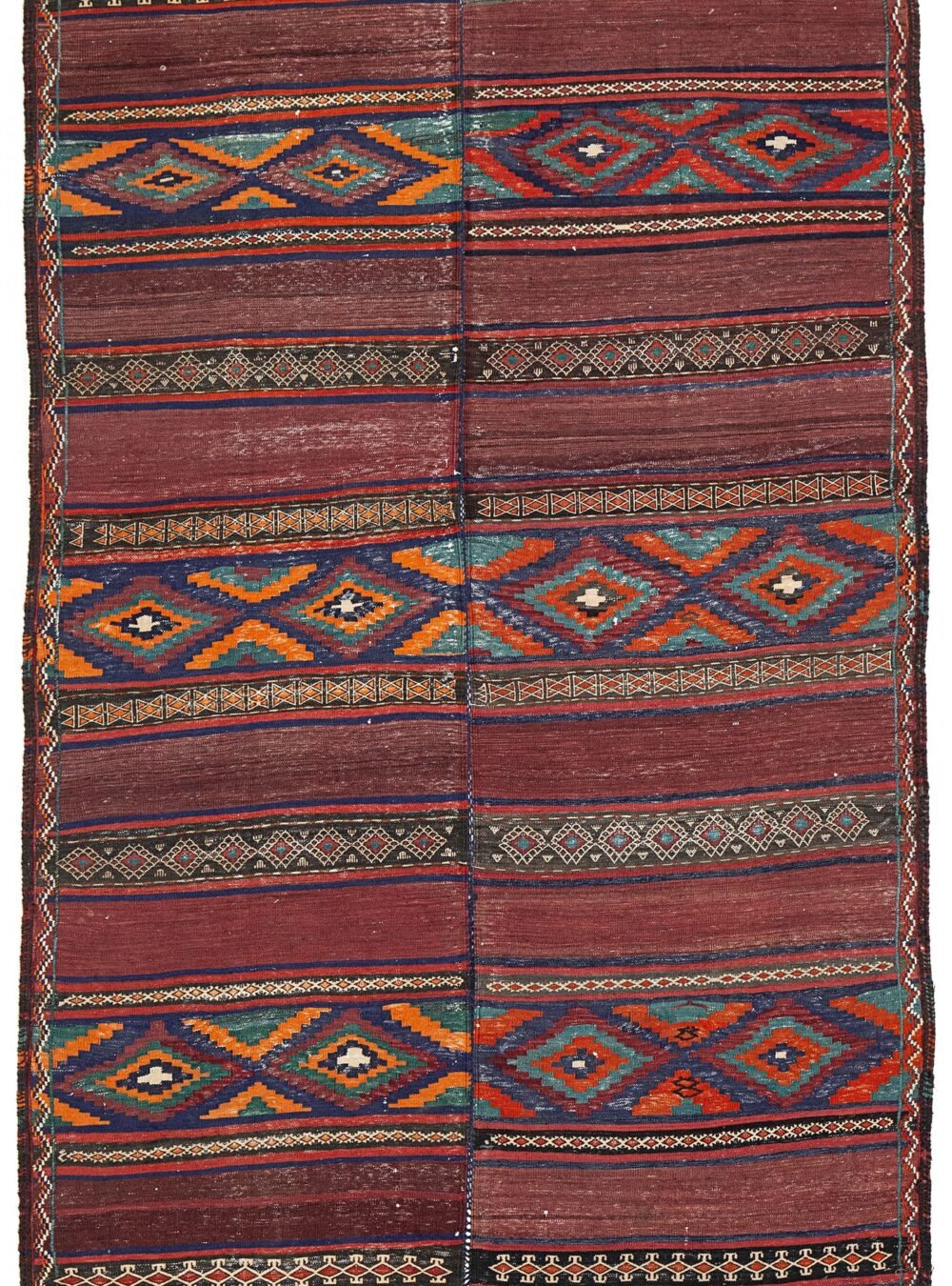 alt="Antique Baluch kilim from East Iran with lozenge motifs" alt="Finely woven tribal kilim in two sections sewn together" alt="Vintage Persian kilim with narrow bands and wide multicoloured patterns" alt="Baluch flatweave rug with symbolic lozenges and rich tribal character"