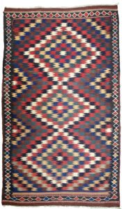 alt="Antique Varamin kilim rug with eye dazzler design from Central Iran" alt="Room-size Persian kilim with geometric lozenge border and tribal motif" alt="Rare Varamin kilim with weaver's mark and traditional flatweave" alt="Collectible Persian flatweave rug in earthy tones with bold design"