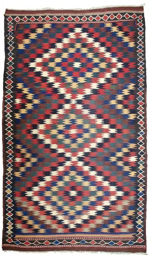 alt="Antique Varamin kilim rug with eye dazzler design from Central Iran" alt="Room-size Persian kilim with geometric lozenge border and tribal motif" alt="Rare Varamin kilim with weaver's mark and traditional flatweave" alt="Collectible Persian flatweave rug in earthy tones with bold design"