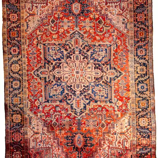 alt="Heriz carpet with bold medallion and terracotta red ground" alt="Persian rug with white spandrels and geometric design" alt="Classic Heriz rug with flowing border and good pile" alt="Antique Heriz carpet with minor wear and strong colours"