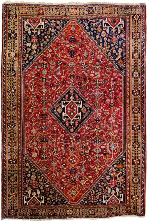 alt="Tribal rug with blue medallion and scarab beetle on terracotta ground" alt="Nomadic Persian rug with symbolic motifs and stylised border" alt="High-quality wool rug with tribal design and missing end knots" alt="Terracotta field tribal carpet with blue medallion and shrub border"