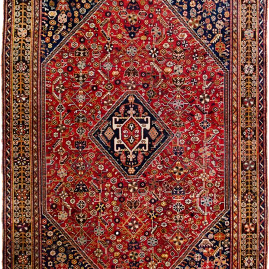 alt="Tribal rug with blue medallion and scarab beetle on terracotta ground" alt="Nomadic Persian rug with symbolic motifs and stylised border" alt="High-quality wool rug with tribal design and missing end knots" alt="Terracotta field tribal carpet with blue medallion and shrub border"