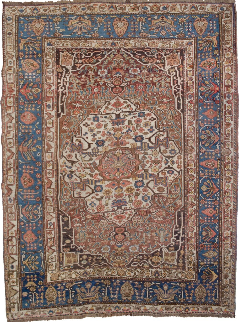 alt="Vintage Khamseh rug with cream medallion and floral motifs on reddish-brown field" alt="Persian carpet with cypress tree border and Bakhtiari-influenced design" alt="Handwoven squarish Khamseh rug with blue border and beige field" alt="Unique Persian rug with geometric guard borders and soft floral elements"